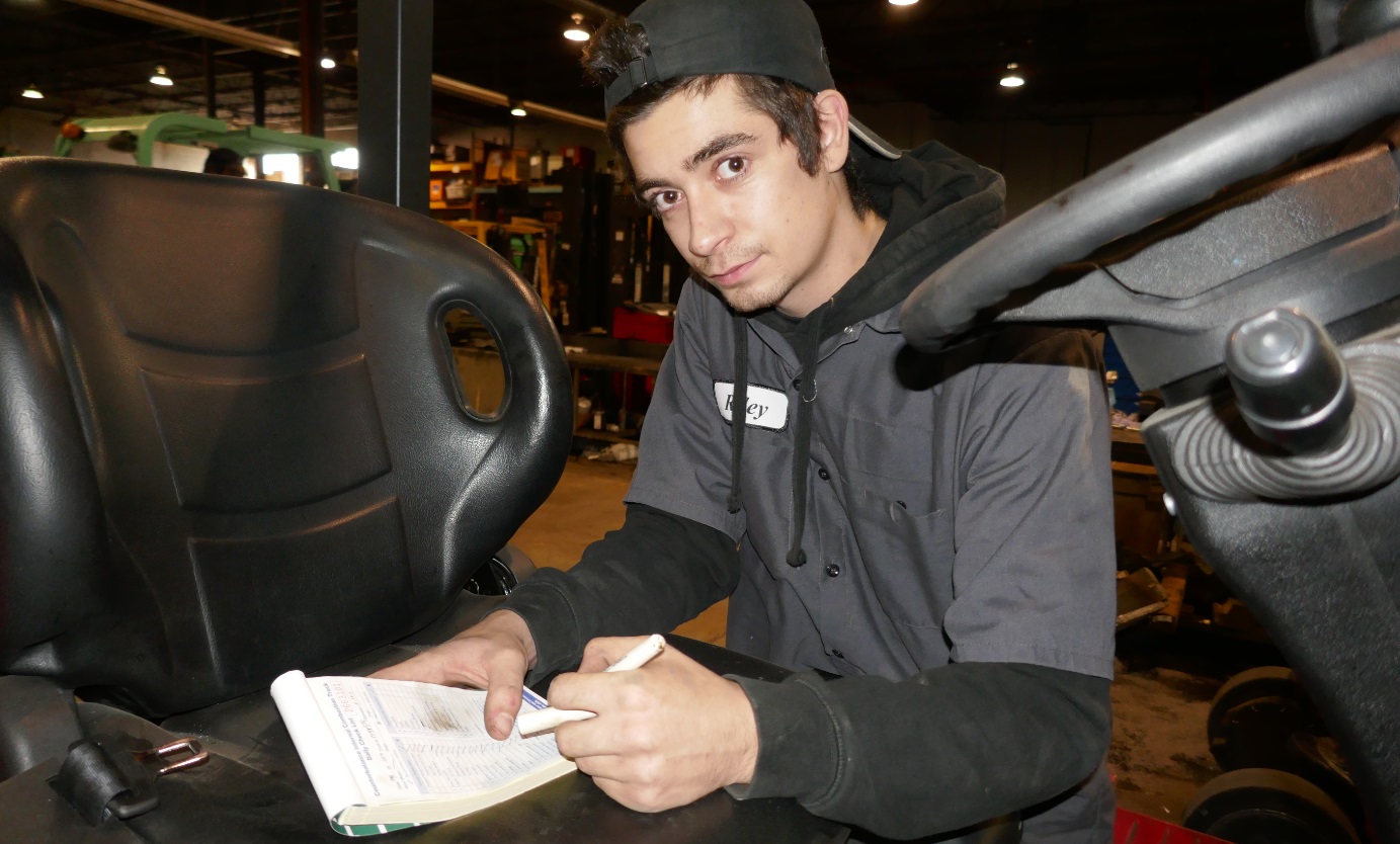 forklift operator completes daily safety check on paper logbook